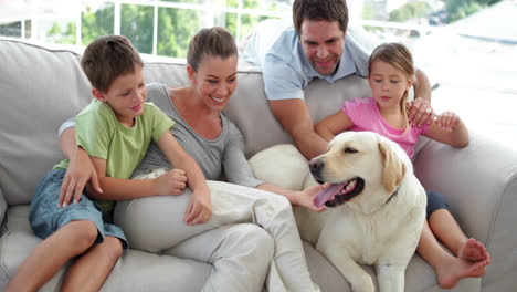 Süße-Familie-Entspannt-Sich-Zusammen-Mit-Ihrem-Hund-Auf-Der-Couch