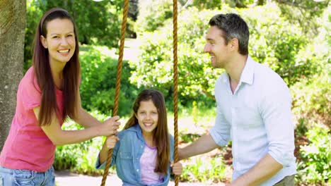 Parents-pushing-their-daughter-on-a-swing-in-the-park