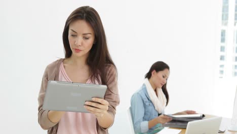 Creative-businesswoman-using-tablet-with-colleague-behind-her