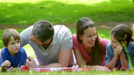 Cute-family-lying-on-a-blanket-in-the-park-and-chatting