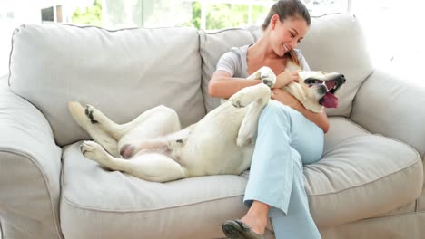 Lachende-Frau-Streichelt-Ihren-Labrador-Hund-Auf-Der-Couch