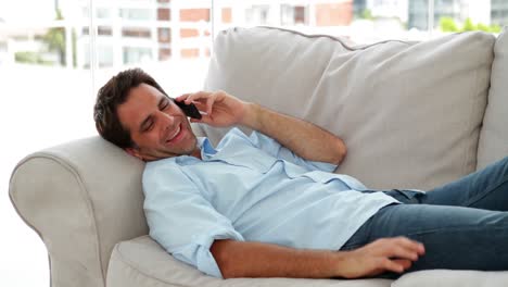 Casual-man-lying-on-the-sofa-chatting-on-the-phone