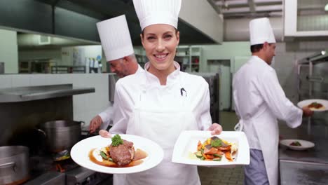 Smiling-chef-showing-two-dishes-to-camera