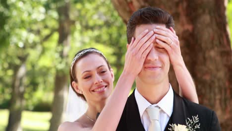 Bride-covering-her-grooms-eyes-and-smiling-at-camera
