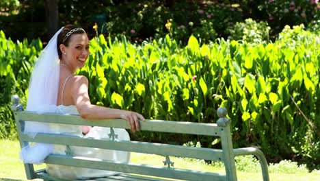 Beautiful-bride-smiling-at-camera-sitting-on-bench