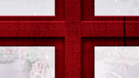 Roter-Holzfensterrahmen-Gegen-Schnee,-Der-über-Mehrere-Häuser-In-Der-Winterlandschaft-Fällt
