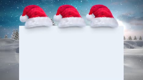 Three-santa-hats-over-a-blank-placard-against-snow-falling-on-winter-landscape