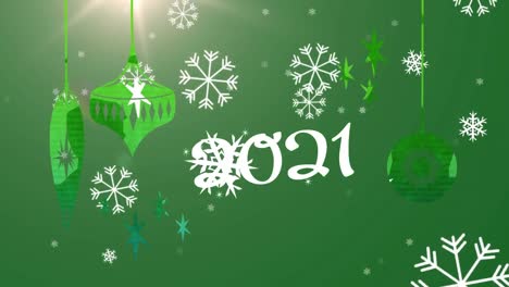 2021-text-and-snowflakes-falling-against-christmas-hanging-decorations-on-green-background