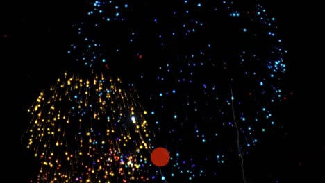 Red-spots-floating-and-colorful-fireworks-exploding-against-black-background