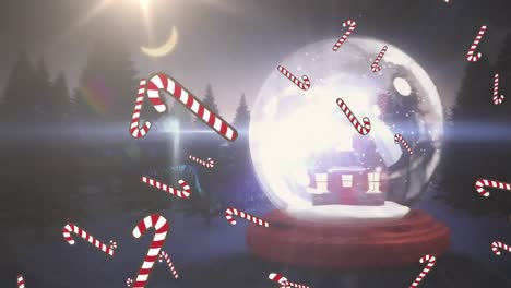 Candy-canes-icons-falling-against-christmas-merry-text-and-house-in-a-snow-globe-on-winter-landscape