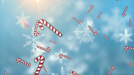 Multiple-candy-icons-cane-falling-and-snowflakes-floating-against-spot-of-light-on-blue-background