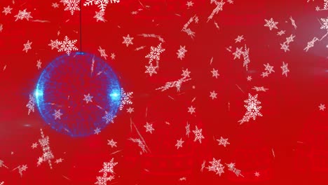 Snowflakes-falling-over-blue-christmas-bauble-hanging-decorations-against-red-background