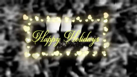 Decorative-heart-shaped-fairy-lights-and-happy-holidays-text-against-black-background