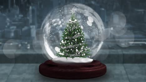 Blue-shooting-star-spinning-around-christmas-tree-in-a-snow-globe-on-wooden-surface