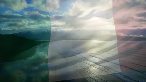 Animation-of-flag-of-italy-waving-over-beach-landscape,-cloudy-blue-sky-and-sea