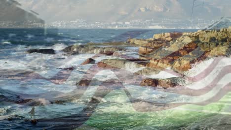 Digital-composition-of-waving-us-flag-against-sea-waves-hitting-the-rocks