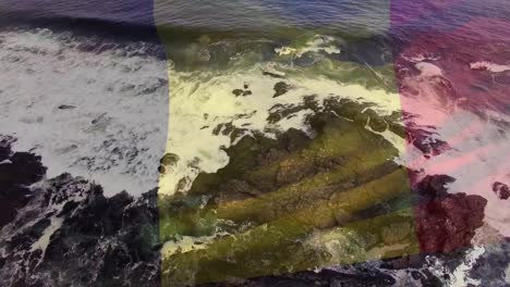Digitale-Komposition-Einer-Schwenkenden-Belgischen-Flagge-Gegen-Meereswellen,-Die-Auf-Die-Felsen-Schlagen