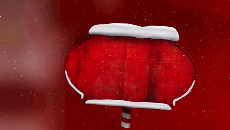 Snow-falling-over-red-wooden-sign-post-against-red-background