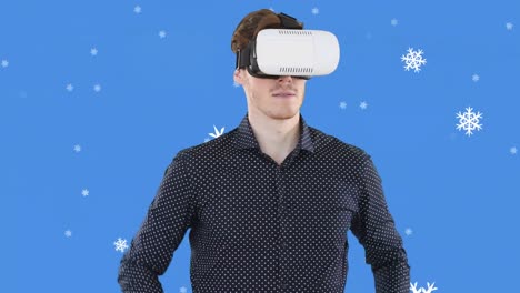 Animation-of-snowflakes-falling-over-man-in-vr-headset,-on-blue-background