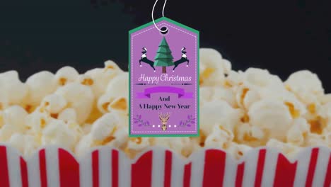 Animation-Von-Weihnachtsgrüßen-Auf-Einem-Etikett-über-Popcorn-Auf-Schwarzem-Hintergrund