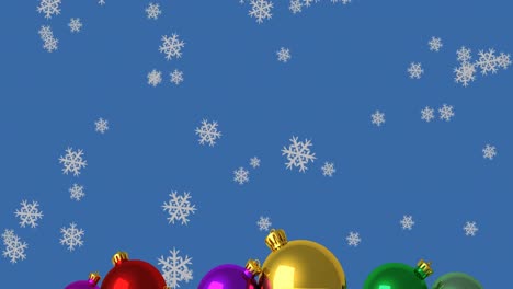 Animation-Von-Schneeflocken,-Die-über-Weihnachtskugeln-Auf-Blauem-Hintergrund-Fallen
