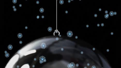 Snow-falling-over-baubles-on-black-background