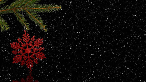 Animation-of-snow-falling-over-red-christmas-decoration-on-christmas-tree-over-black-background