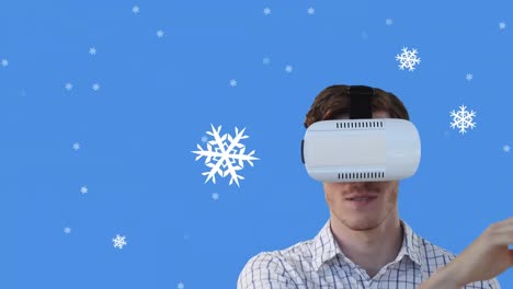 Animation-of-snow-falling-over-man-wearing-vr-glasses-on-blue-background