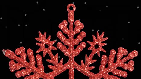 Animation-of-snow-falling-over-red-star-christmas-decoration-on-black-background