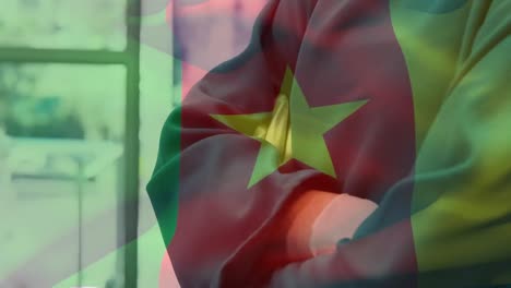 Animation-of-flag-of-cameroon-waving-over-surgeon-in-operating-theatre