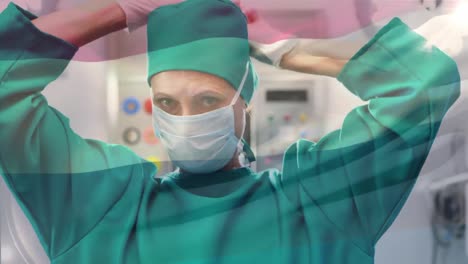 Animation-of-flag-of-netherlands-waving-over-female-surgeon-in-operating-theatre