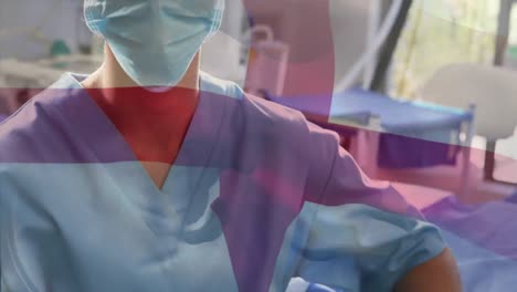 Animation-of-flag-of-england-waving-over-female-surgeon-in-operating-theatre