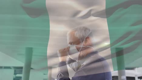 Animation-Der-Flagge-Nigerias,-Die-über-Einem-Kaukasischen-Mann-Mit-Gesichtsmaske-In-Der-Stadtstraße-Weht