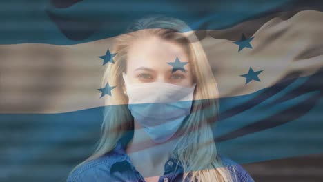 Animation-of-flag-of-honduras-waving-over-woman-wearing-face-mask-during-covid-19-pandemic