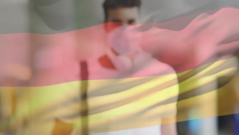 Animation-of-flag-of-germany-waving-over-man-wearing-face-mask-during-covid-19-pandemic