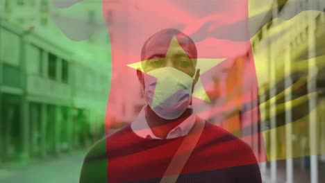 Animation-of-flag-of-cameroon-waving-over-african-american-man-wearing-face-mask-in-city-street