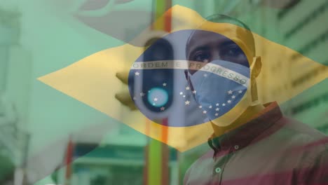 Animation-of-flag-of-brazil-waving-over-african-american-man-wearing-face-mask-in-city-street