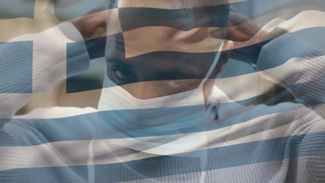 Animation-Der-Flagge-Griechenlands,-Die-über-Einem-Afroamerikanischen-Mann-Mit-Gesichtsmaske-In-Der-Stadtstraße-Winkt