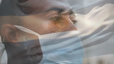 Animation-of-flag-of-argentina-waving-over-man-wearing-face-mask-during-covid-19-pandemic