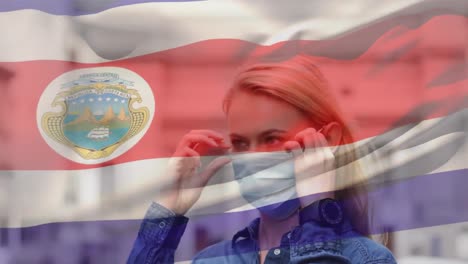 Animation-of-flag-of-costa-rica-waving-over-woman-wearing-face-mask-during-covid-19-pandemic