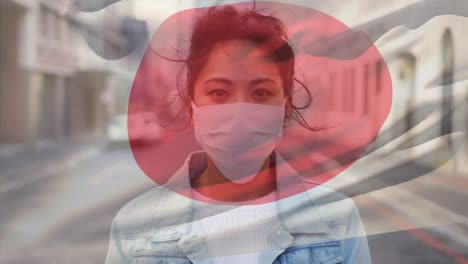 Animation-of-flag-of-japan-waving-over-woman-wearing-face-mask-during-covid-19-pandemic