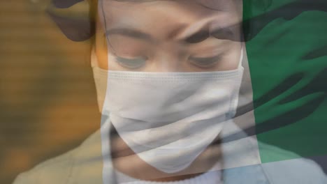 Animation-of-flag-of-ivory-coast-waving-over-woman-wearing-face-mask-during-covid-19-pandemic
