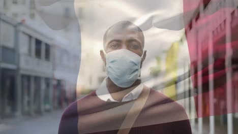 Animation-of-flag-of-france-waving-over-man-wearing-face-mask-during-covid-19-pandemic
