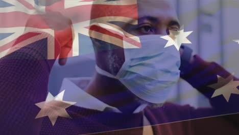 Animation-of-flag-of-australia-waving-over-african-american-man-wearing-face-mask-in-city-street