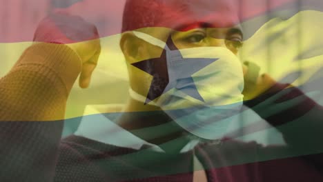 Animation-of-flag-of-ghana-waving-over-man-wearing-face-mask-during-covid-19-pandemic
