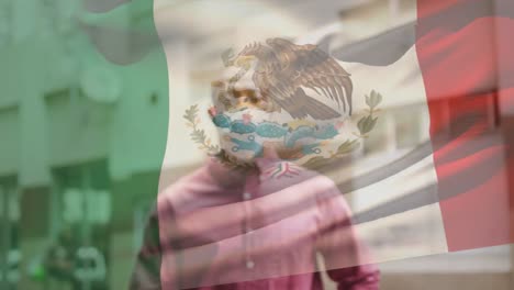 Animation-of-flag-of-mexico-waving-over-african-american-man-wearing-face-mask-in-city-street