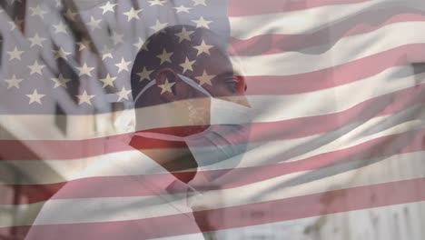 Animation-of-flag-of-usa-waving-over-african-american-man-wearing-face-mask-in-city-street