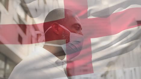 Animation-Der-Flagge-Englands,-Die-Während-Der-Covid-19-Pandemie-über-Einem-Mann-Mit-Gesichtsmaske-Winkt