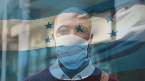 Animation-of-flag-of-honduras-waving-over-african-american-man-wearing-face-mask