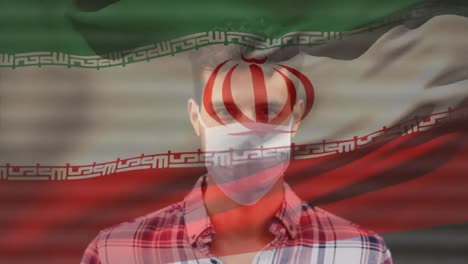 Animation-of-flag-of-iran-waving-over-latin-man-wearing-face-mask-in-city-street